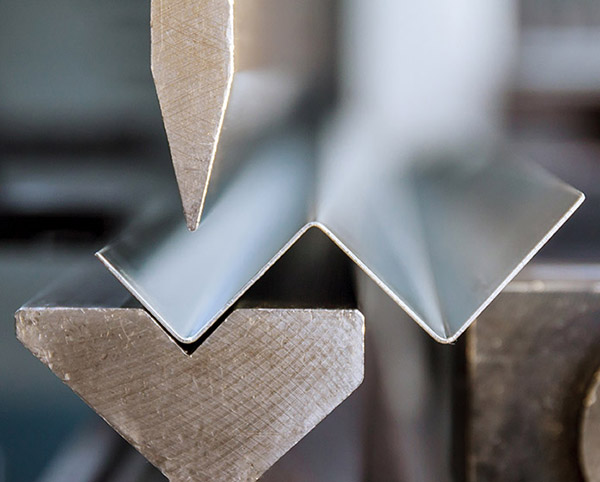 Bending of galvanized sheet metal on a hydraulic bending machine at the factory.